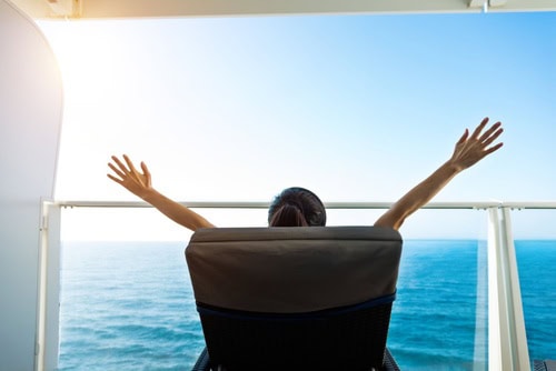 Cruise passenger relaxing on a private balcony overlooking the ocean during a cruise holiday.