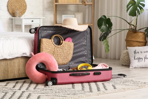 Open suitcase packed with cruise holiday essentials including a sun hat, beach bag and travel accessories.