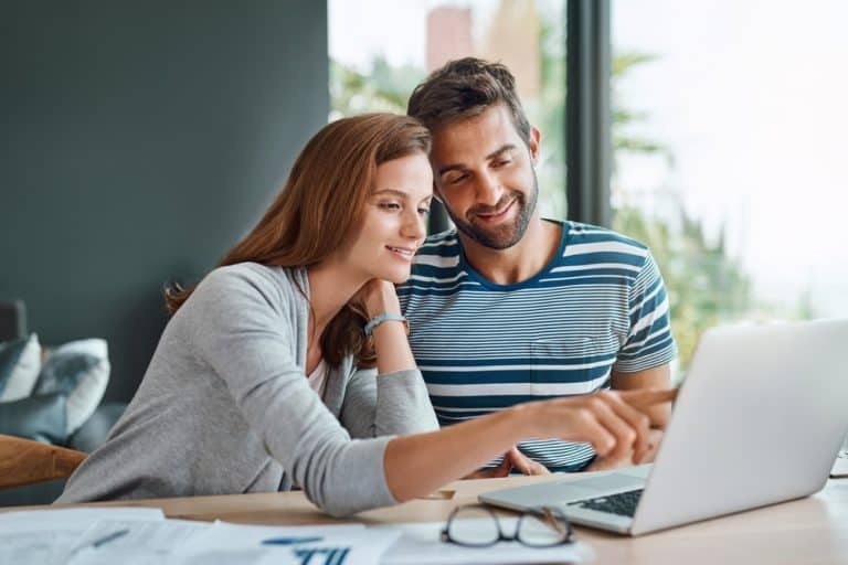 Couple reviewing their finances together on a laptop while planning their household budget and future expenses.