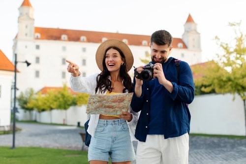 Couple sightseeing on holiday with a map and camera while exploring a historic European destination on foot.